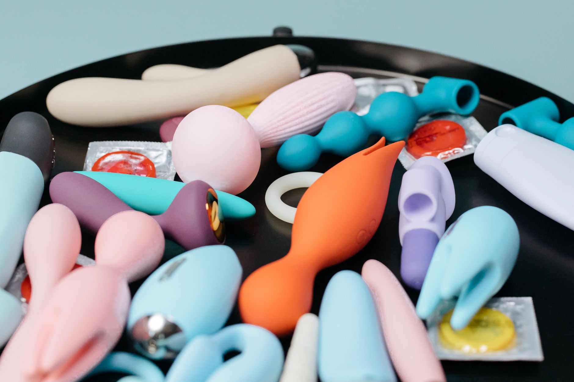 Eine blaue Silikonvibrator wird in der Hand gehalten gegen einen violetten Hintergrund, was Selbstliebe und Sexualität fördert