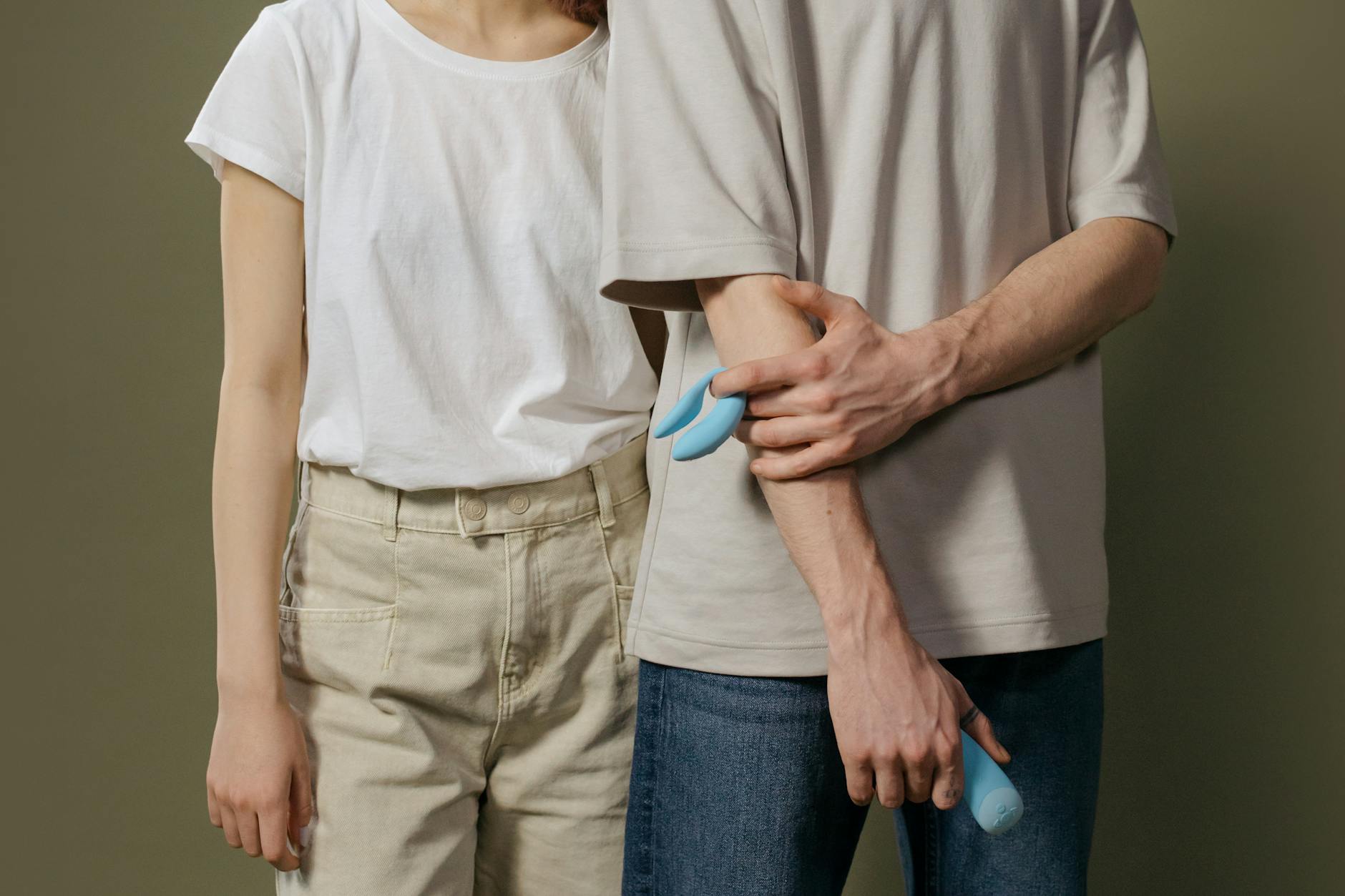 Ein Paar steht zusammen und hält einen blauen Vibrator, was moderne Intimität symbolisiert