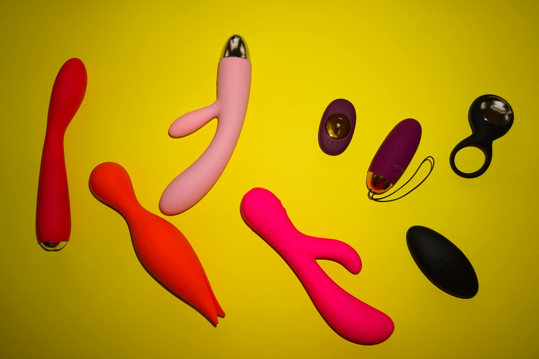 Ein blauer Vibrator umgeben von Blumen und Orangenscheiben auf gelbem Hintergrund