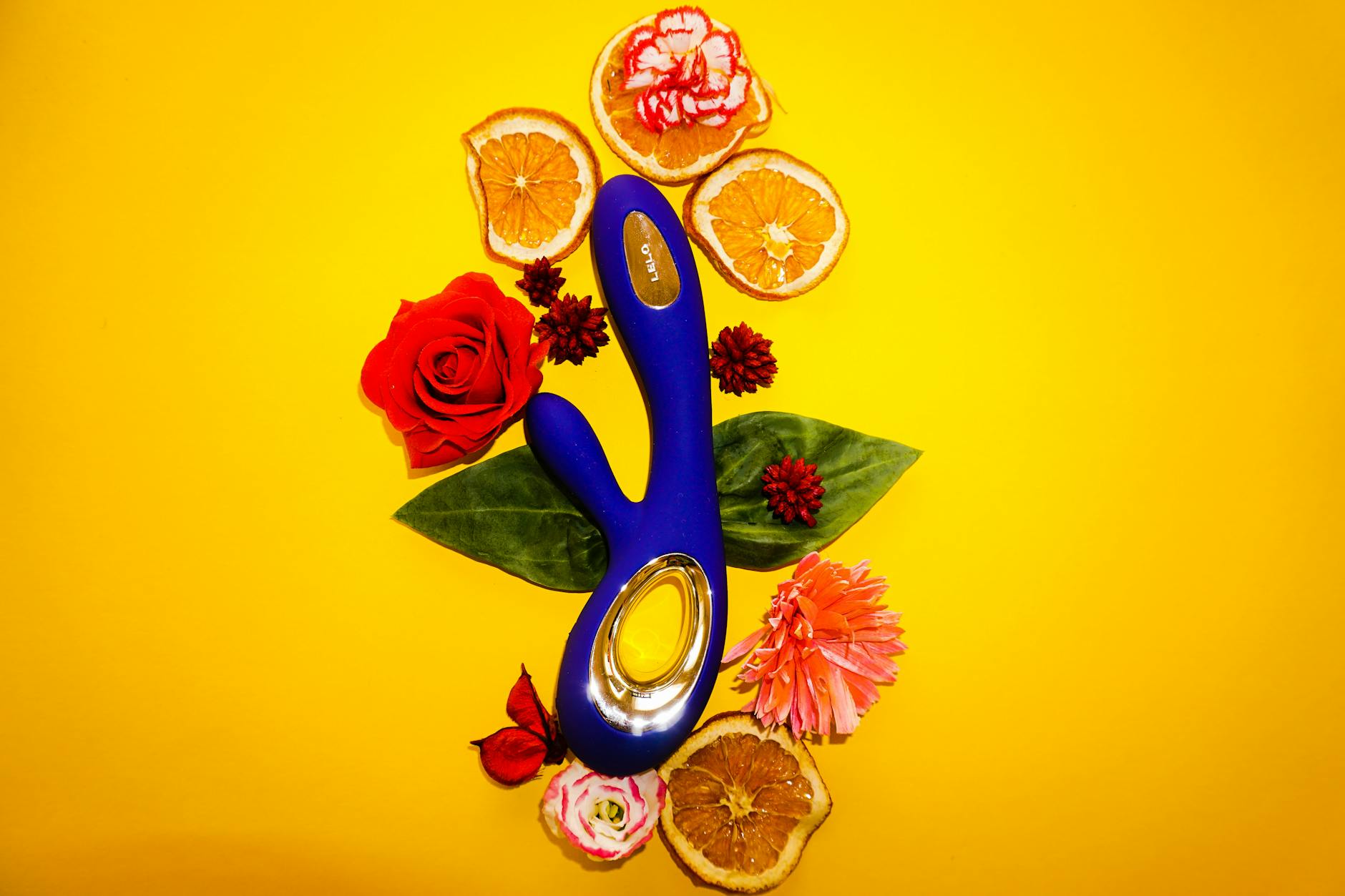 Zwei Hände halten rosa und blaue Silikonvibratoren nebeneinander vor pastellfarbenem Hintergrund
