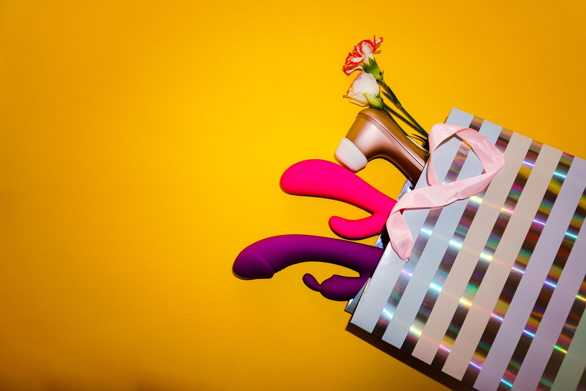 Farbenfrohe Zitronenvibratore mit Blumen in einer holografischen Geschenktasche auf gelbem Hintergrund